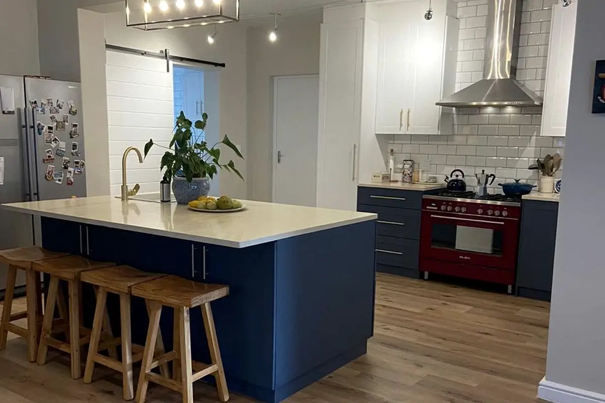 Completed kitchen renovation with a navy island, wooden floors and new lighting
