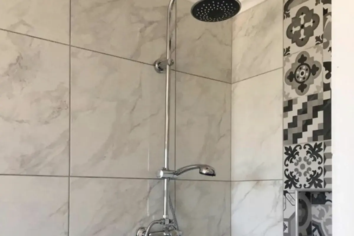 Finished bathroom with a new rain shower, marble-effect tiles and a patterned feature strip