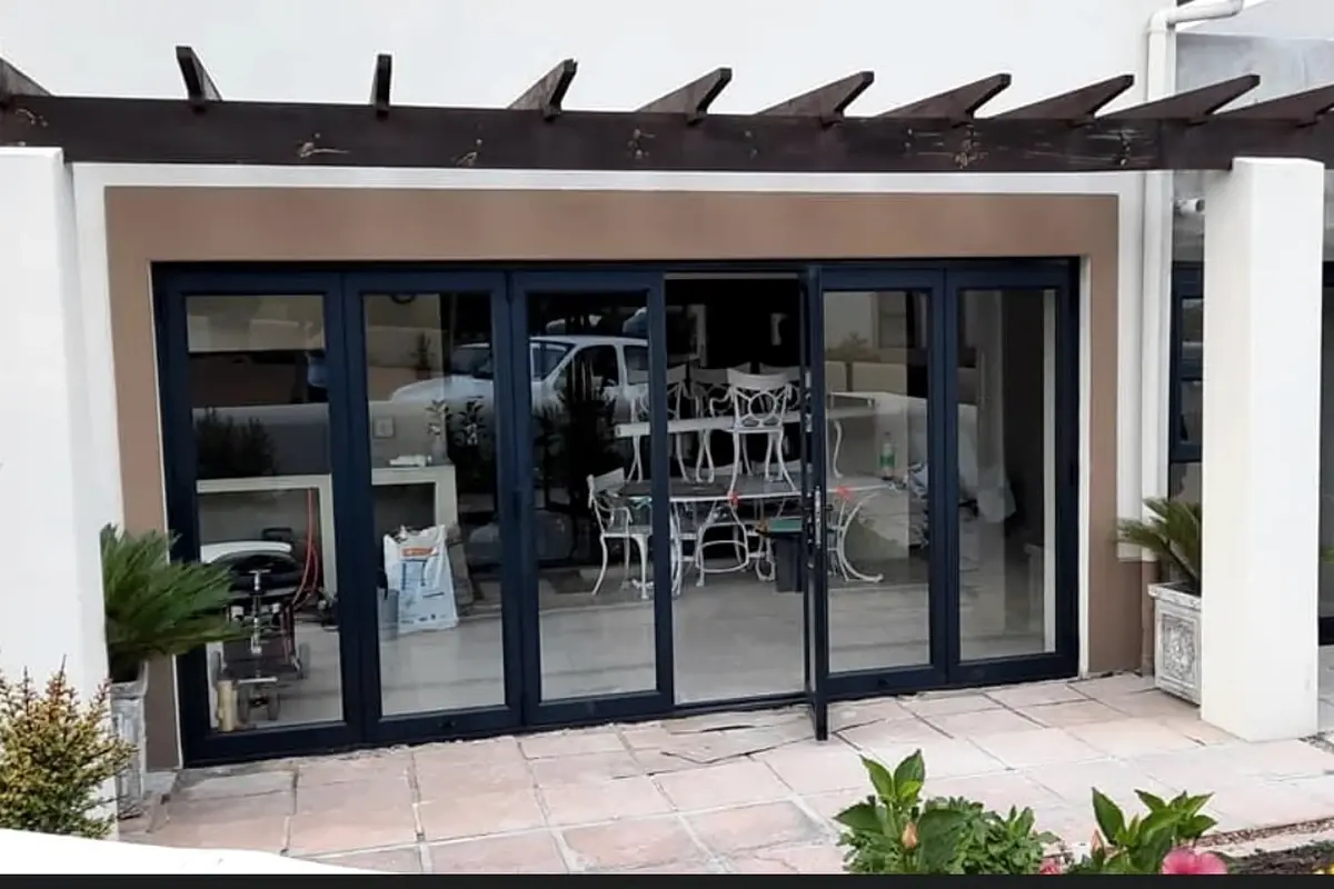 New stacking doors fitted under a timber pergola onto a paved patio