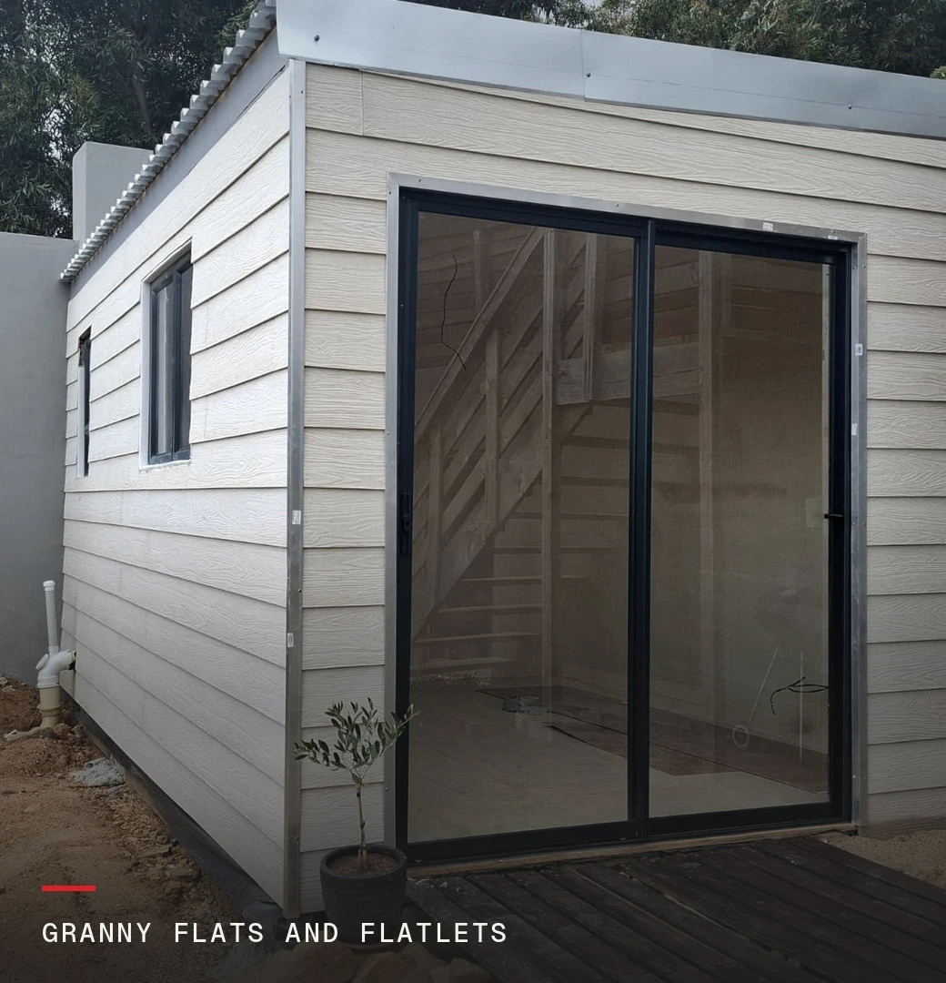A finished granny flat in a Cape Town back garden with sliding doors onto a timber deck, labelled: granny flats and flatlets.
